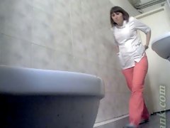 Mature white lady in pink pants urinates in the public restroom